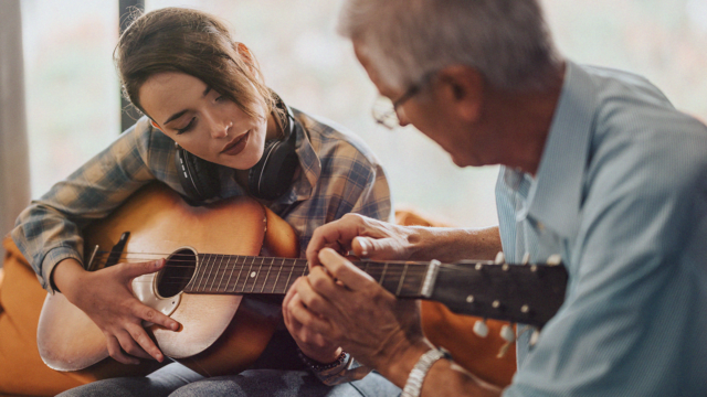 Volwassene leert onder begeleiding van een muziekdocent akoestische gitaar spelen