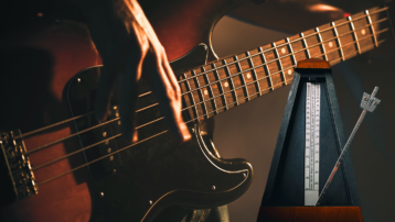 Close-up van een bassist die zijn timing verfijnt met een mechanische metronoom