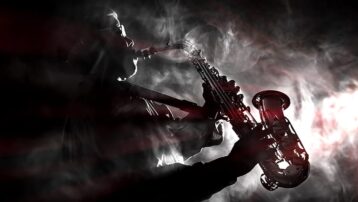 Silhouet van een saxofonist spelend in een mysterieuze, rokerige sfeer, die de iconische niet-gitaarsolo’s uit onze blog over legendarische instrumentale prestaties weerspiegelt.