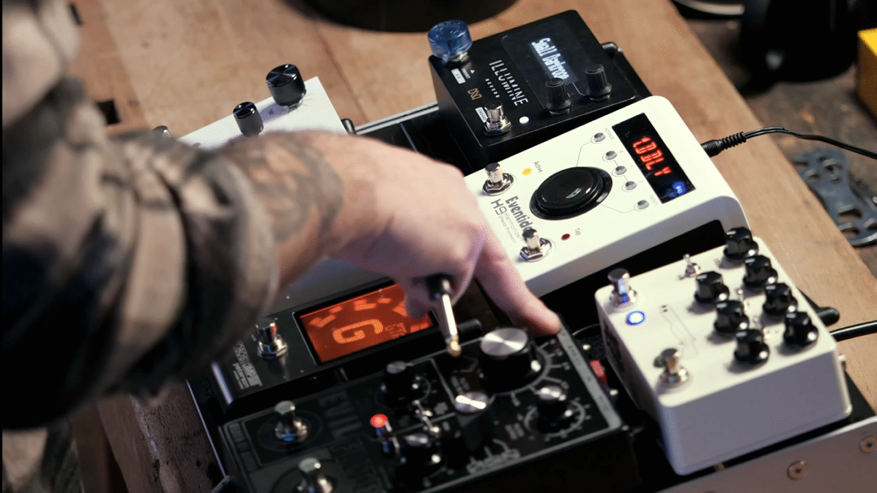 Close-up van een gitarist die aan de knoppen draait van een pedalboard vol effecten in een studiosetting. Pedalboard Basics: Zo organiseer je jouw effectenketen