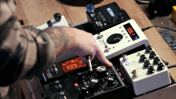 Close-up van een gitarist die aan de knoppen draait van een pedalboard vol effecten in een studiosetting. Pedalboard Basics: Zo organiseer je jouw effectenketen