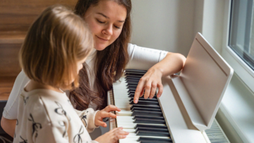 Volwassene leert een kind thuis keyboard spelen