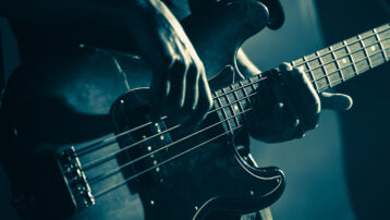 Close-up van een bassist die live op het podium speelt, uitgelicht in de blog “De beste bassolo’s uit de muziekgeschiedenis”