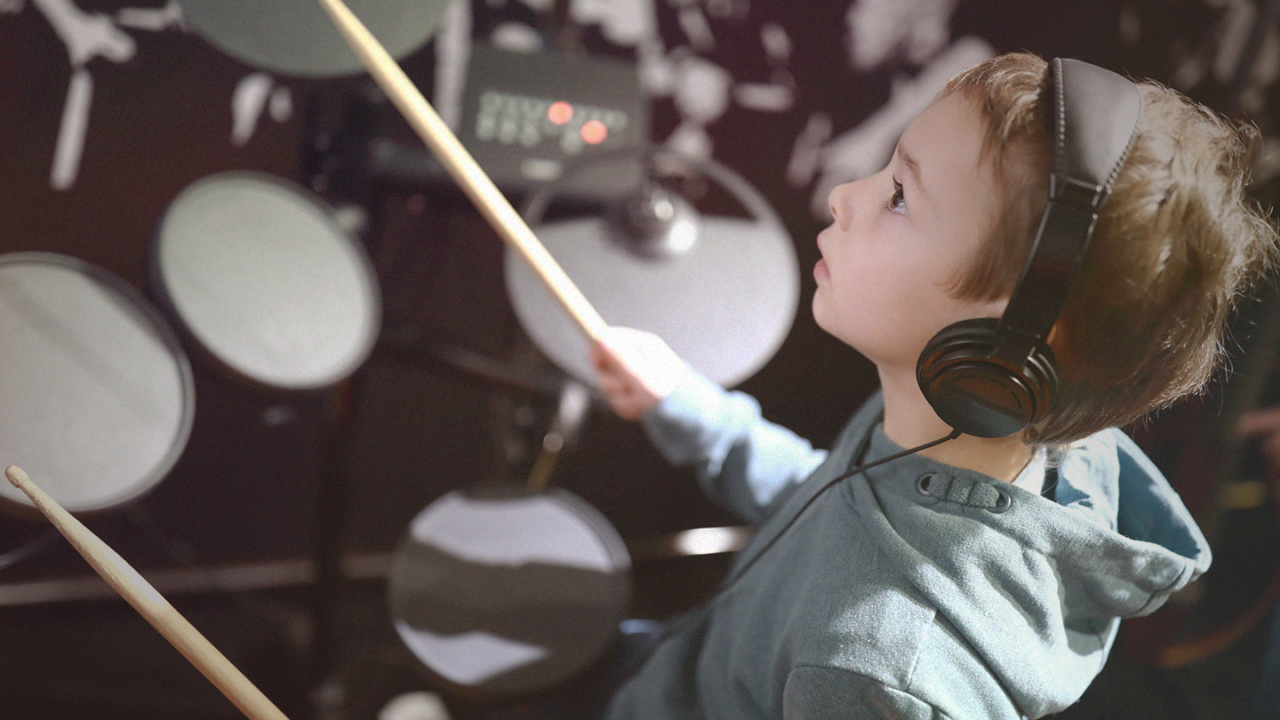 Jonge drummer speelt op een elektronisch drumstel met een koptelefoon op