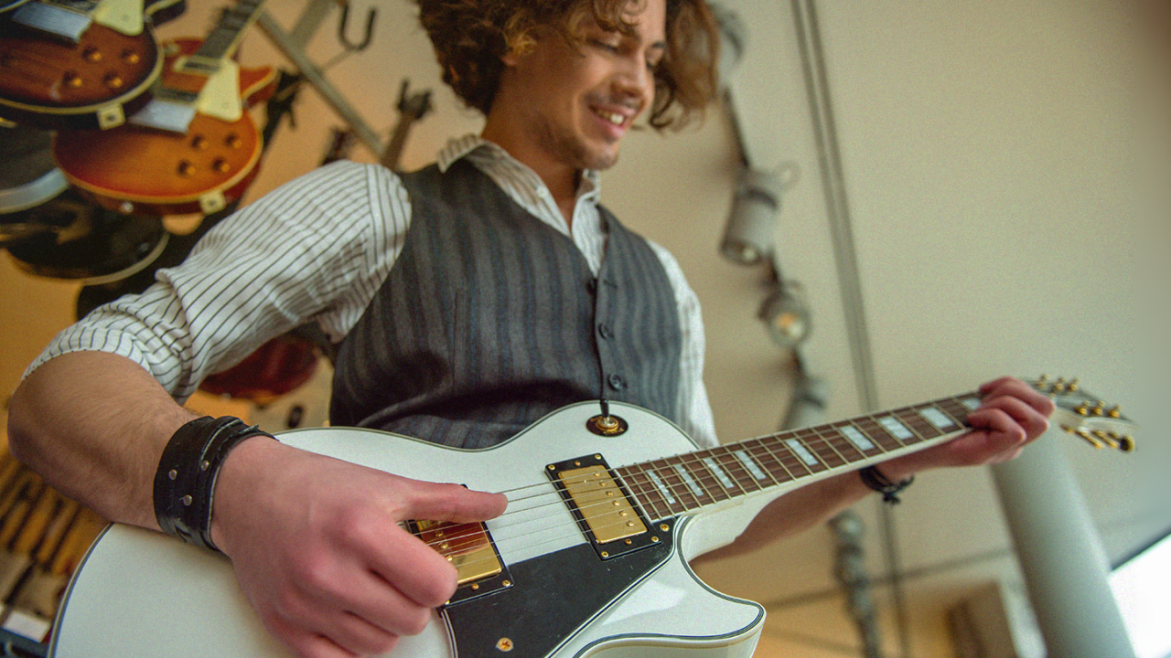 Beginnende gitarist speelt op een witte elektrische gitaar in een gitaarwinkel