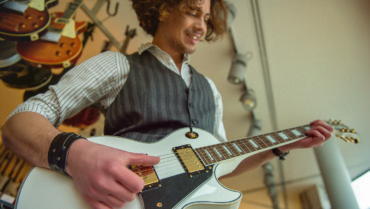 Beginnende gitarist speelt op een witte elektrische gitaar in een gitaarwinkel