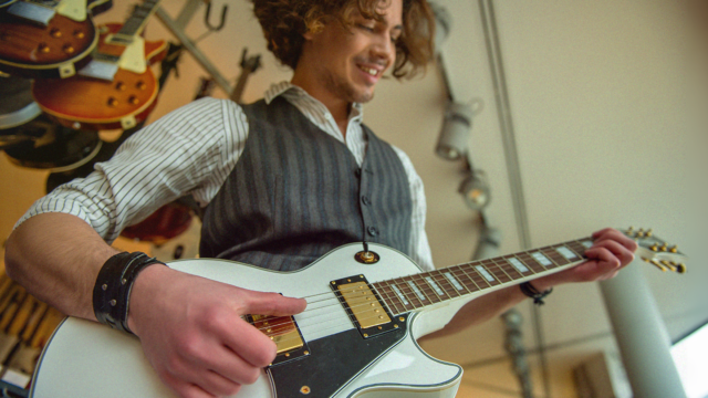 Beginnende gitarist speelt op een witte elektrische gitaar in een gitaarwinkel
