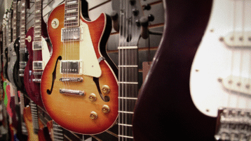 Een close-up van verschillende elektrische gitaren, waaronder Les Paul- en Stratocaster-modellen, opgesteld in een muziekwinkel – ideaal voor beginners die hun eerste instrument gaan ontdekken.