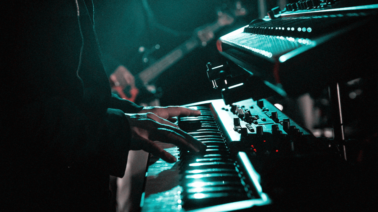 Keyboards Live: Van Stands tot Bekabeling – Close-up van een muzikant die live keyboards speelt, omringd door synthesizers en stage-verlichting.