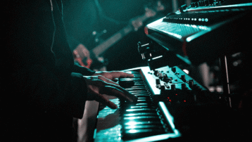 Keyboards Live: Van Stands tot Bekabeling – Close-up van een muzikant die live keyboards speelt, omringd door synthesizers en stage-verlichting.
