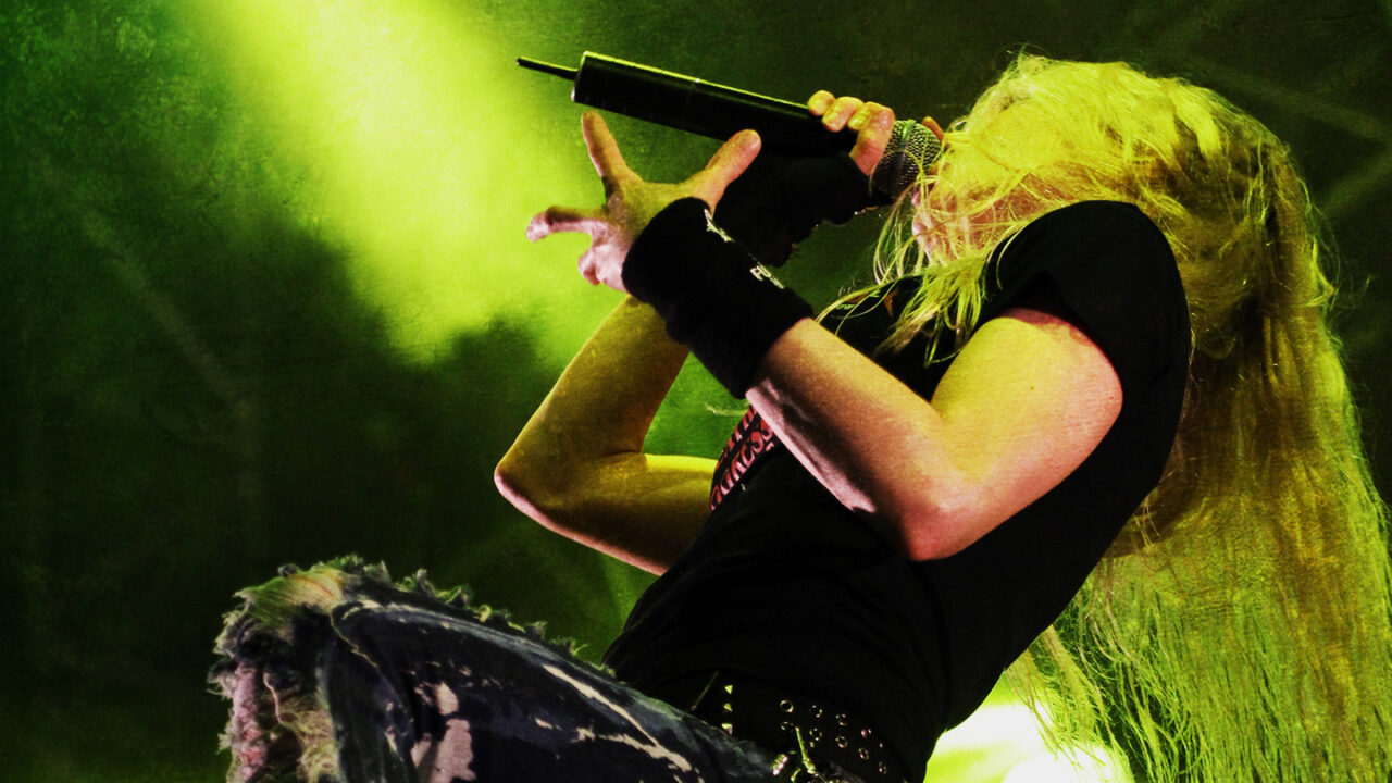 Vrouwelijke metalzangeres die live op het podium optreedt met een microfoon en dramatische belichting tijdens een heavy metalconcert