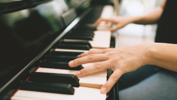 Close-up van handen op een pianoklavier, die de toegankelijkheid en efficiëntie van hedendaags pianoleren voor zowel beginners als volwassen leerlingen onderstreept.