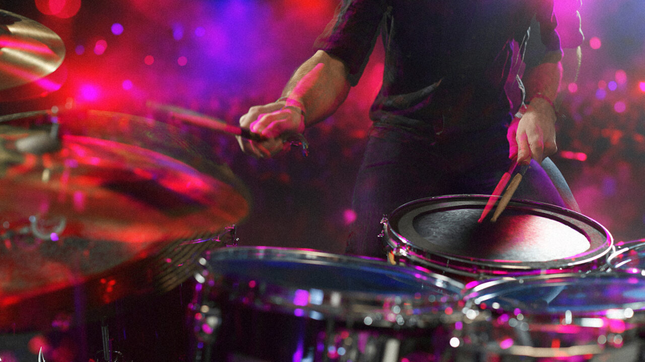 Drummer die een energieke drumfill speelt op het podium, met kleurrijke belichting tijdens een liveconcert