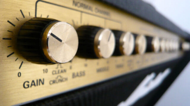 Close-up van de regelaars van een gitaarversterker met gain- en EQ-instellingen.