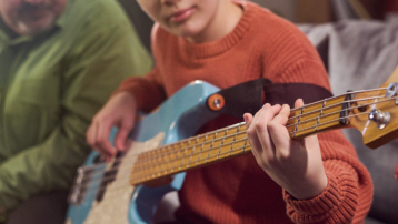 Jonge muzikant oefent op elektrische bas tijdens het leren bespelen van een instrument