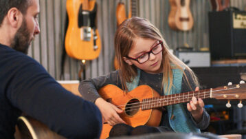 Kind leert akoestische gitaar spelen met een muziekdocent – zo kies je je eerste instrument