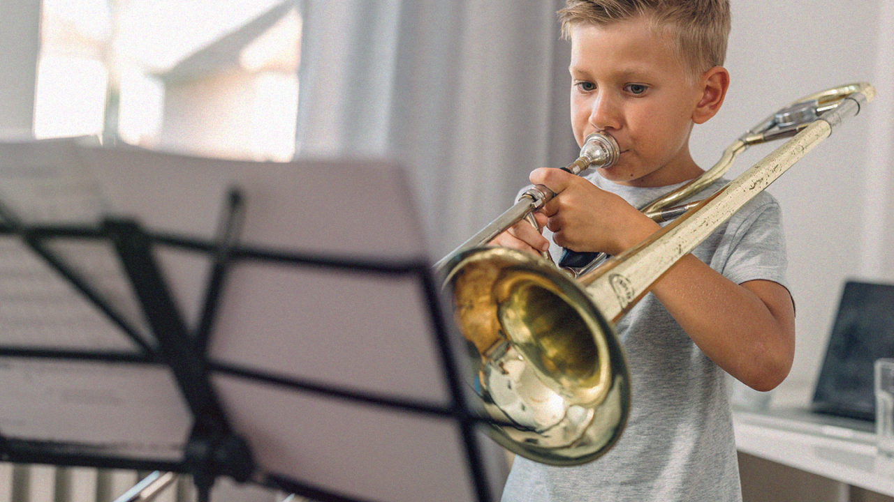 Jonge muzikant speelt trombone. Trompet, trombone of euphonium: welk instrument past bij jou?