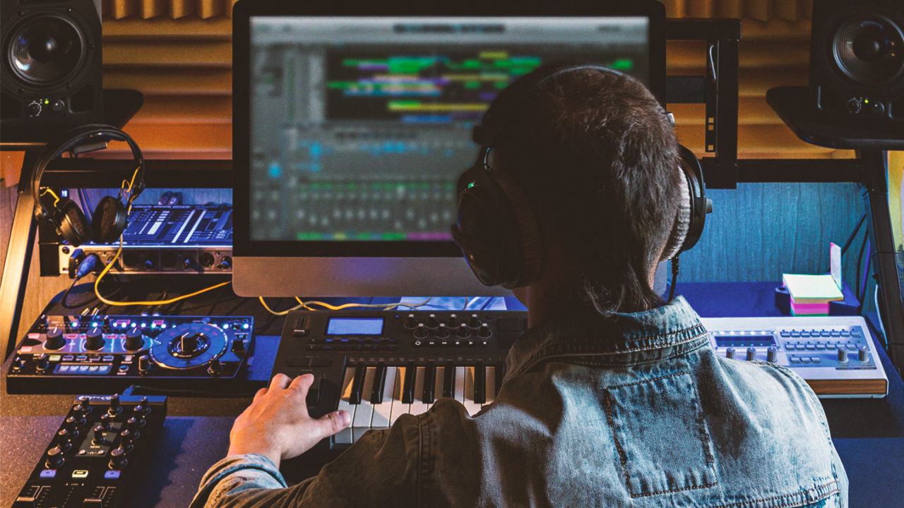 Muziekproducer aan het werk in een homestudio met studiomonitoren, MIDI-keyboard en audioapparatuur