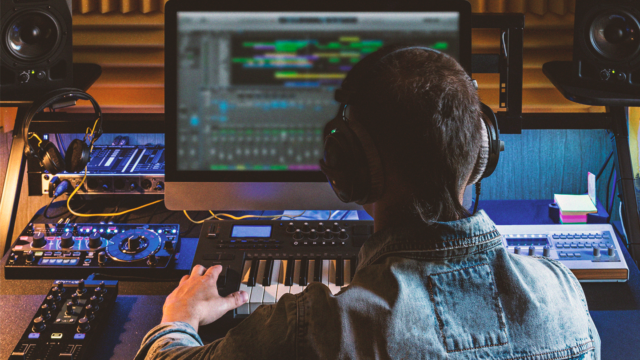 Muziekproducer aan het werk in een homestudio met studiomonitoren, MIDI-keyboard en audioapparatuur