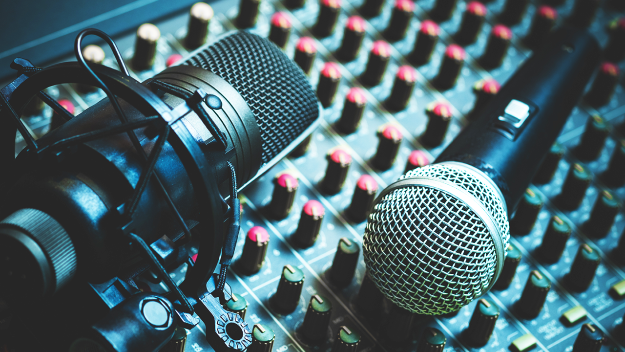 Condensatormicrofoon in een shockmount en dynamische handheldmicrofoon op een audiomengpaneel