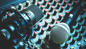 Condensatormicrofoon in een shockmount en dynamische handheldmicrofoon op een audiomengpaneel